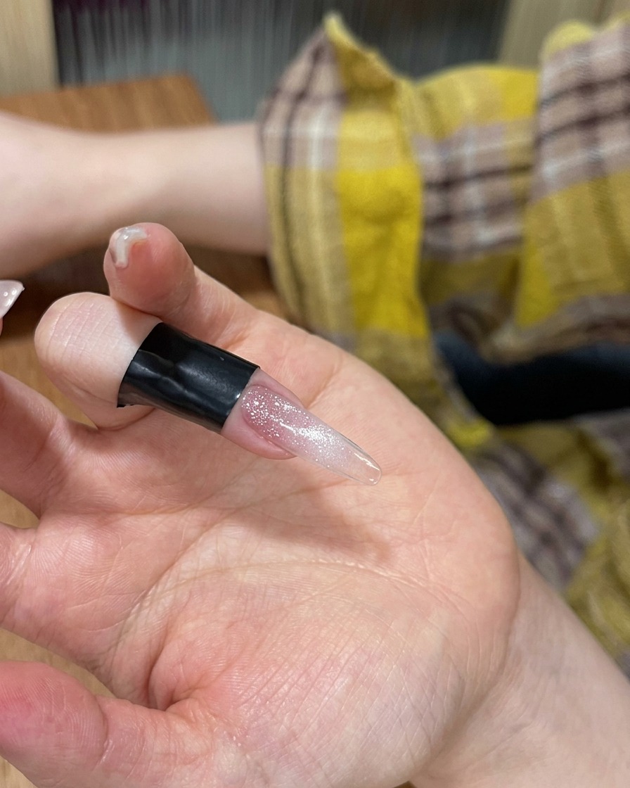 Gros plan dun doigt avec du vernis cat-eye sous une lampe LED portable.