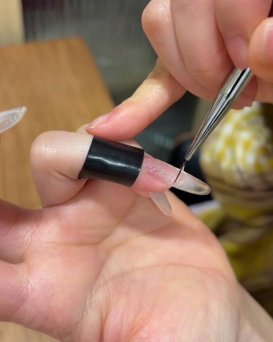 Une petite quantité de gel adhésif transparent appliquée au centre de longle.