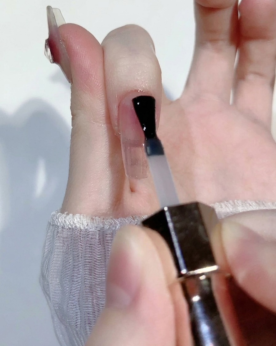 Perle de gel blush rose transparent appliquée au centre dun ongle transparent.