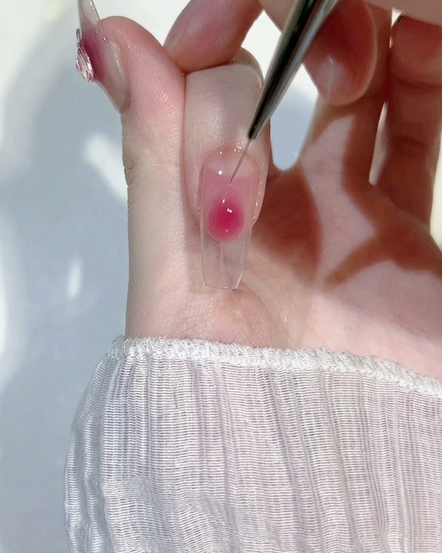 Gros plan dun pinceau liner estompant du gel rose sur une extension pour un dégradé.