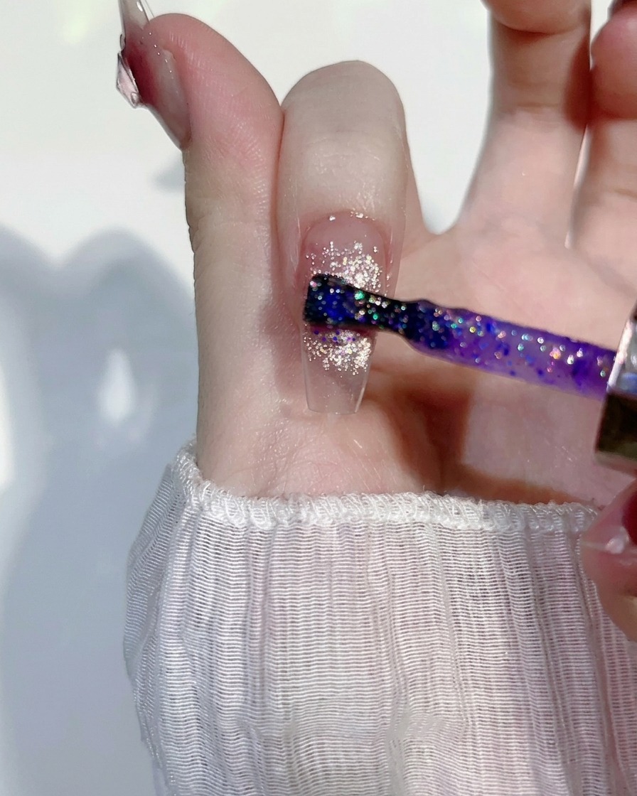 Application dune fine couche de gel pailleté violet sur un design rose.