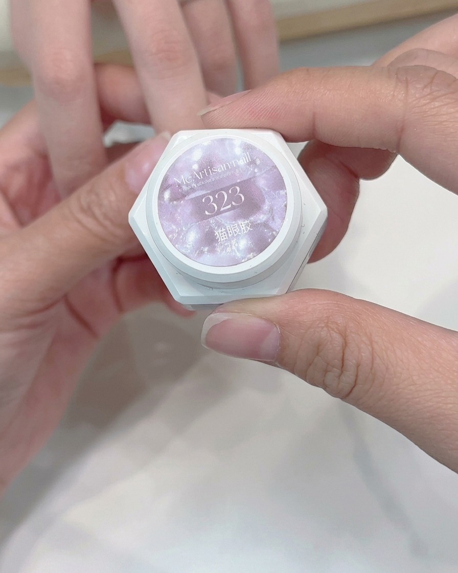 Un pinceau appliquant une couche de gel œil de chat clair sur un ongle.