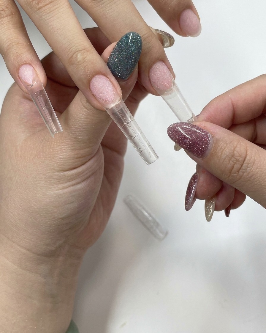 Une main pressant fermement une capsule transparente sur un ongle naturel.