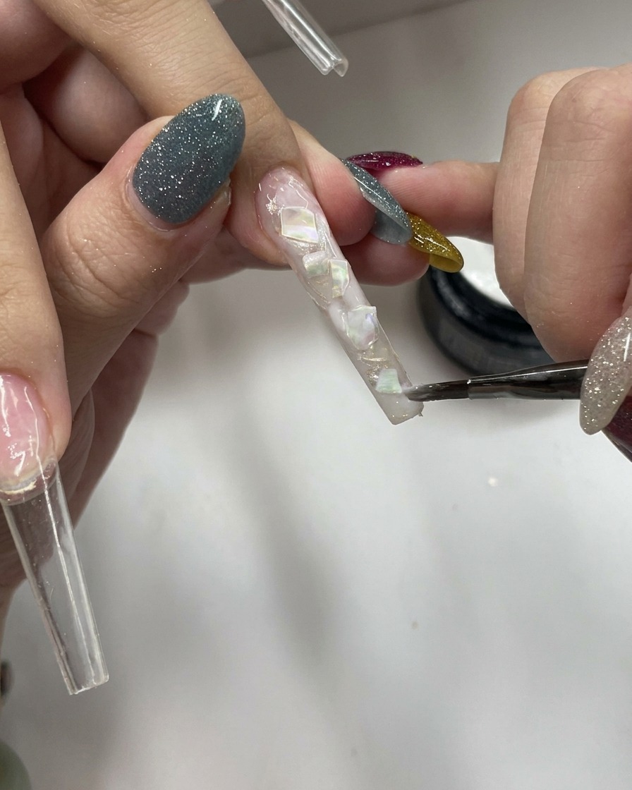Un pinceau appliquant un gel blanc laiteux transparent sur une surface texturée.