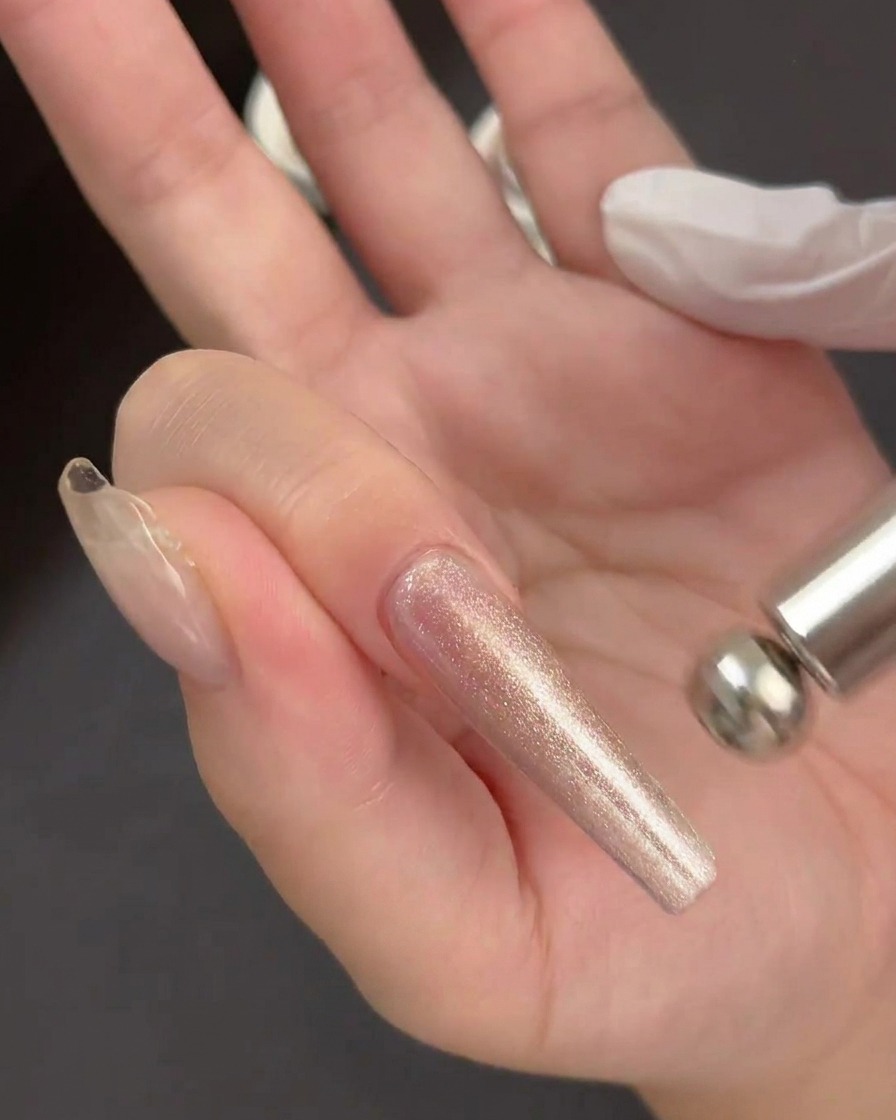 Une main tenant un outil magnétique cylindrique flottant juste au-dessus dune application de gel scintillant humide sur une extension dongle transparente.