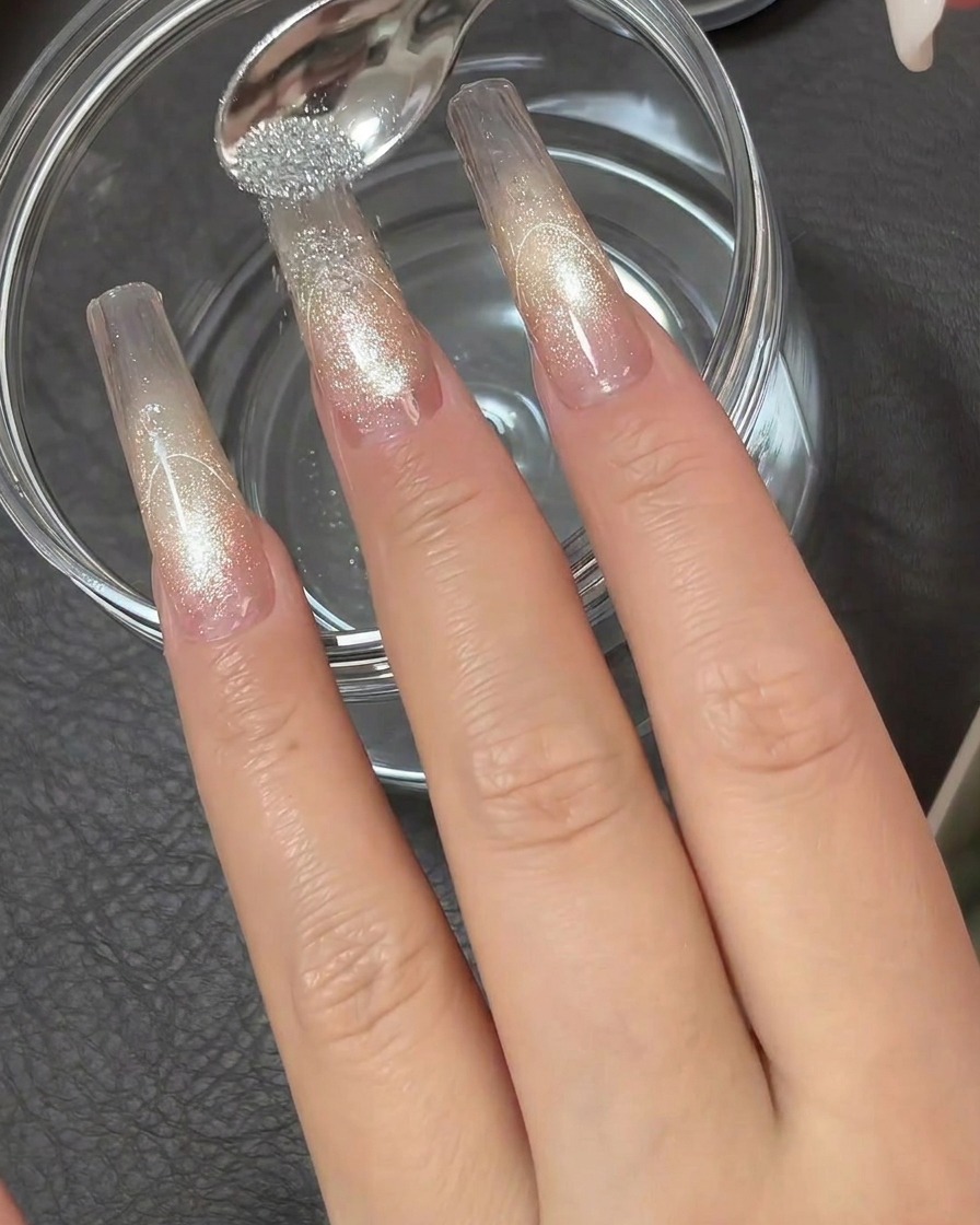 Une petite cuillère en métal saupoudrant une poudre diamant argentée hautement réfléchissante sur la pointe collante dune extension dongle transparente.