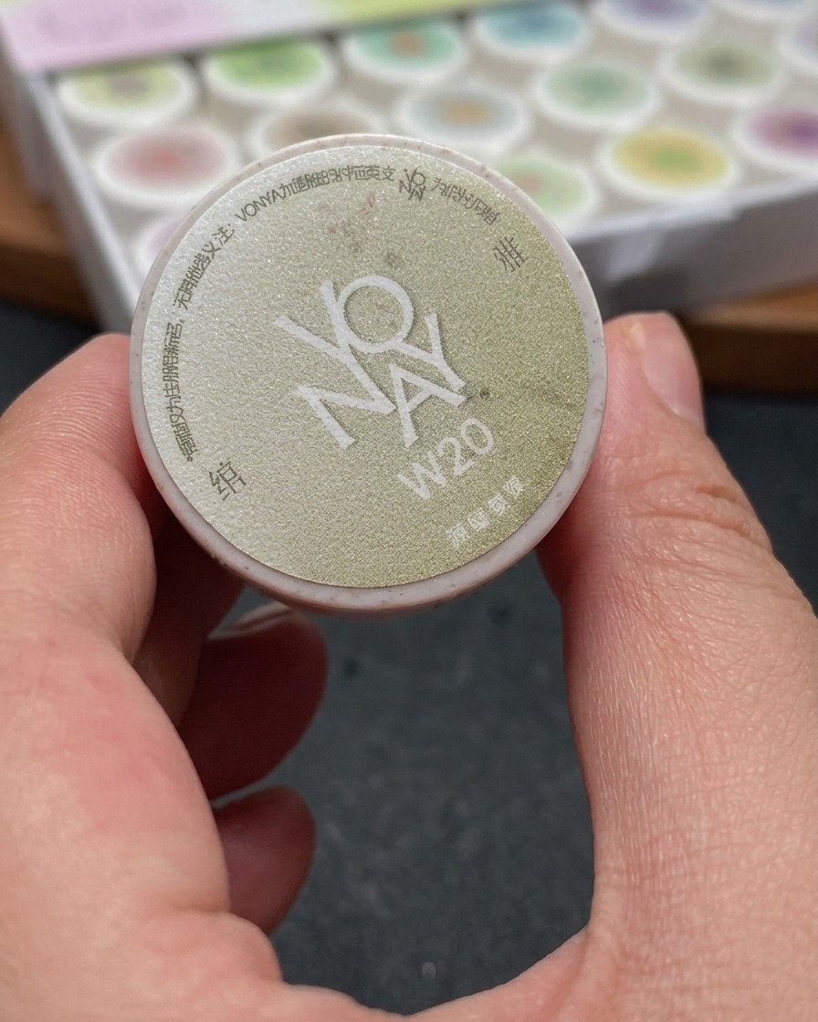 Un pinceau appliquant un gel cat-eye blanc scintillant sur un ongle, couvrant uniformément toute la surface.