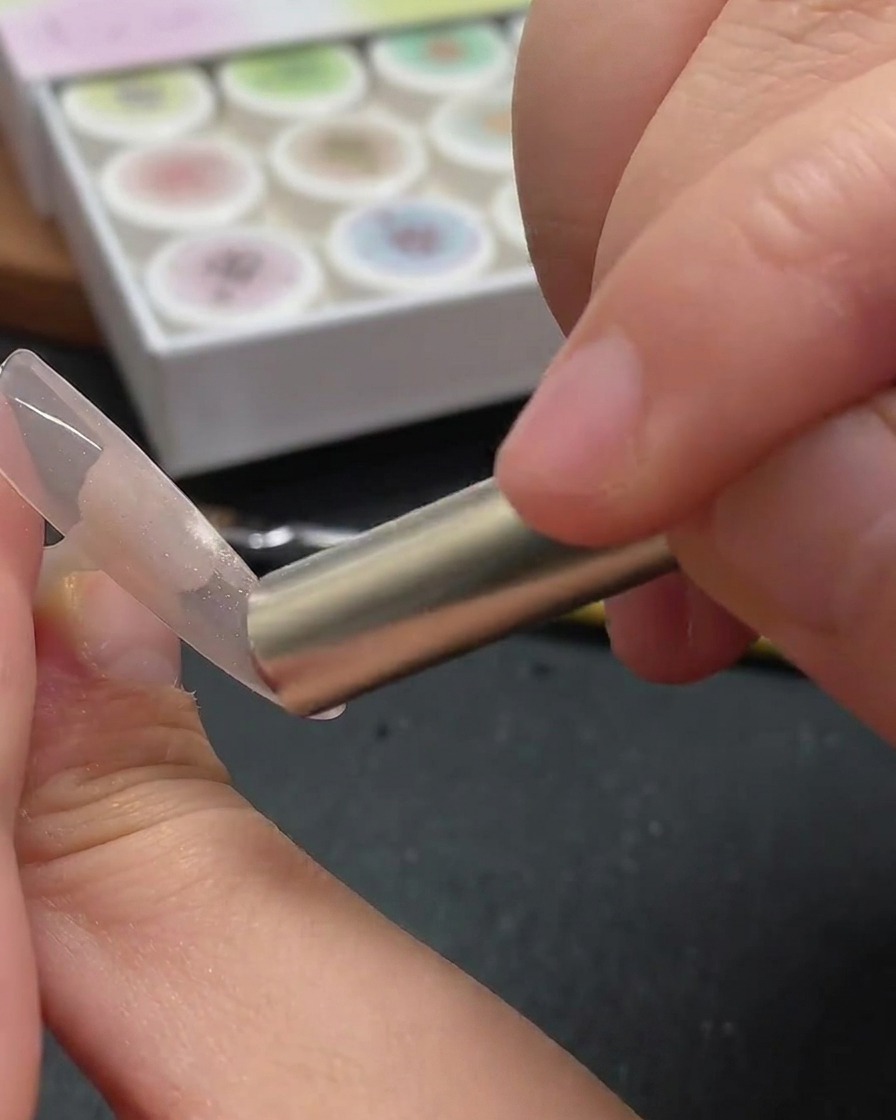 Un ongle illuminé par la lumière violette dune lampe UV/LED, fixant le design cat-eye.
