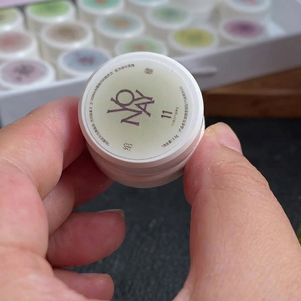 Une petite éponge à maquillage avec des lignes de vernis gel blanc et rouge rosé appliquées sur sa surface.