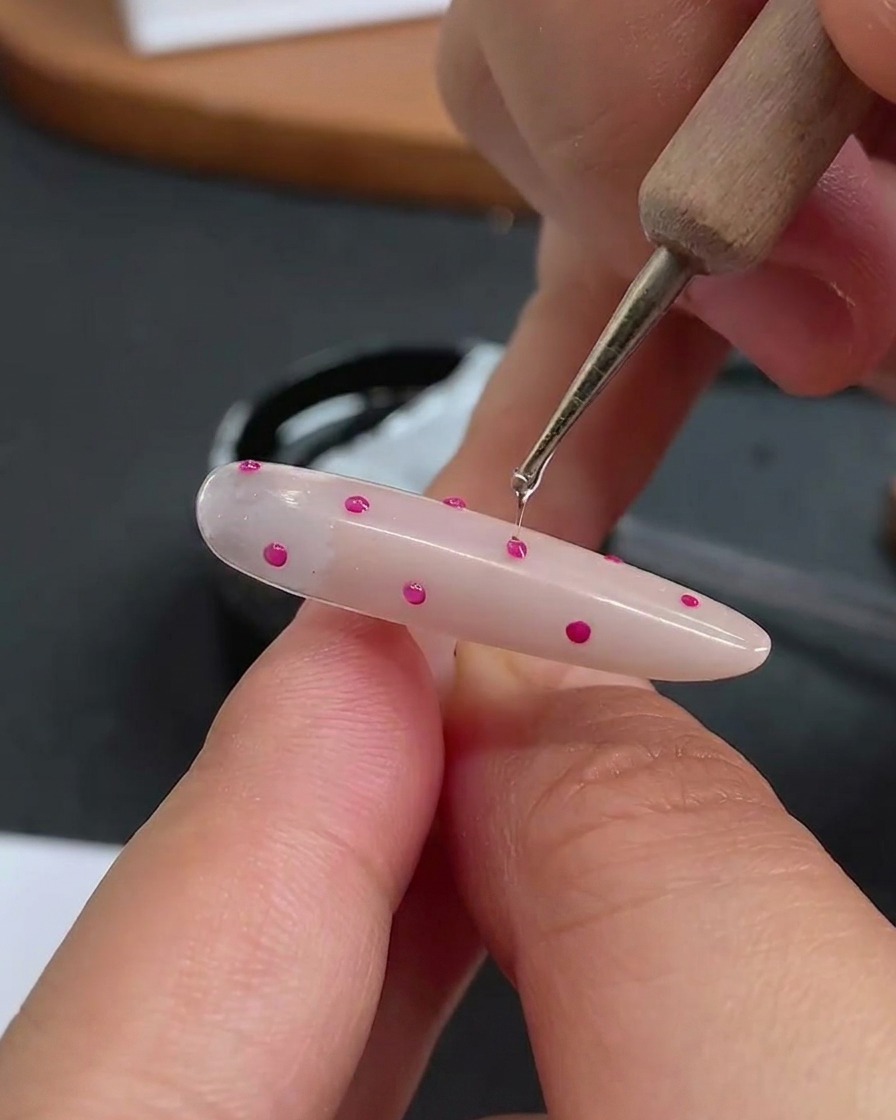 Un outil de dotting appliquant une petite goutte transparente de gel de construction sur chaque pois individuel.