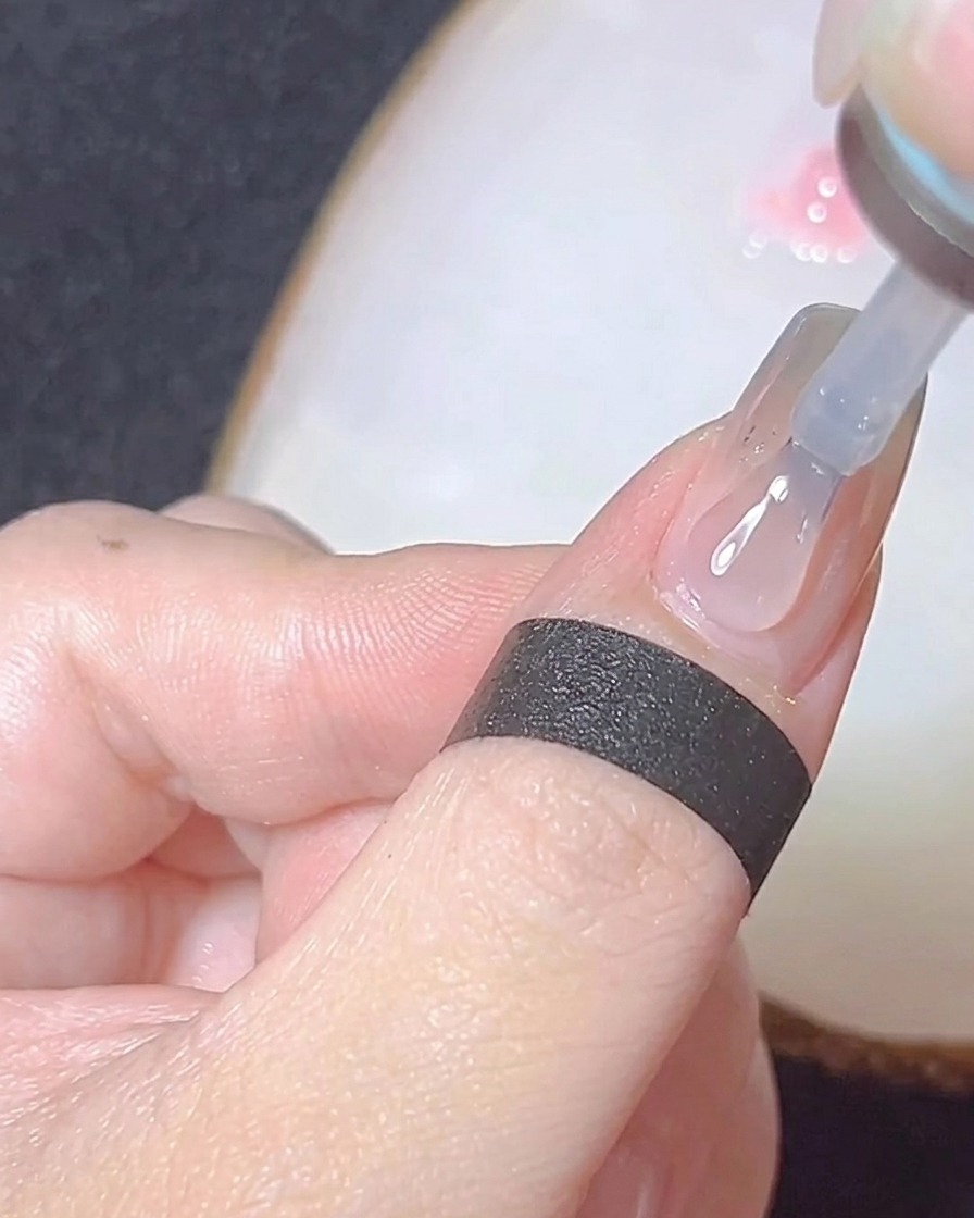 Gros plan dun pinceau appliquant un top coat transparent brillant sur un ongle fini chromé.