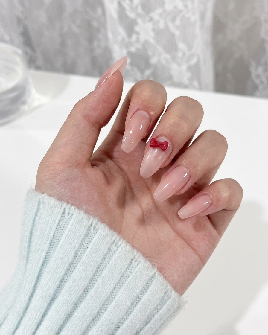 Un pinceau de détail peignant de petites formes dyeux rouges sur un ongle sous un nœud.