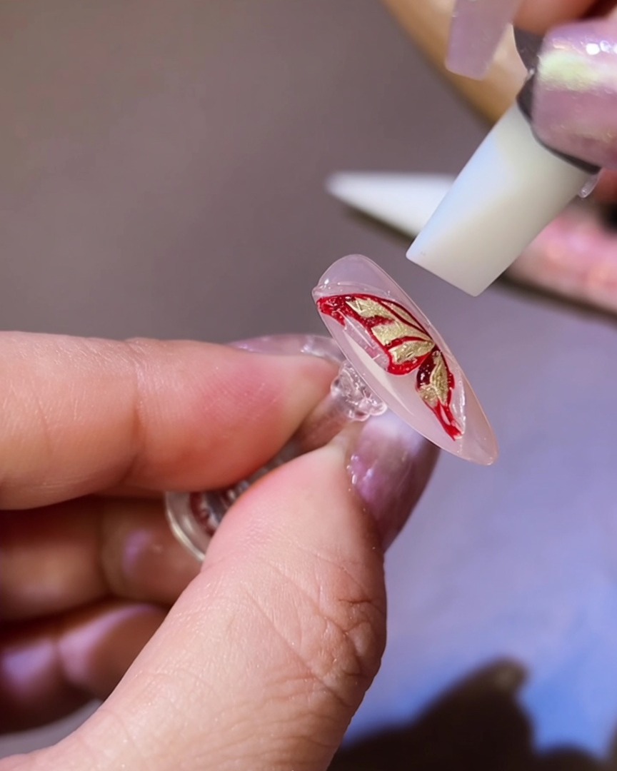 Un outil en silicone façonnant le gel 3D en une silhouette daile de papillon sur longle.