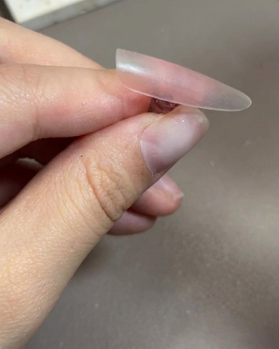 Une main placée à lintérieur dune lampe à ongles UV/LED professionnelle, avec les ongles bien visibles sous la lumière.
