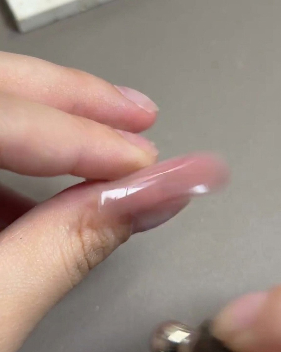 Un outil magnétique tourné dans un mouvement circulaire autour dun ongle pour former un reflet sphérique brillant.