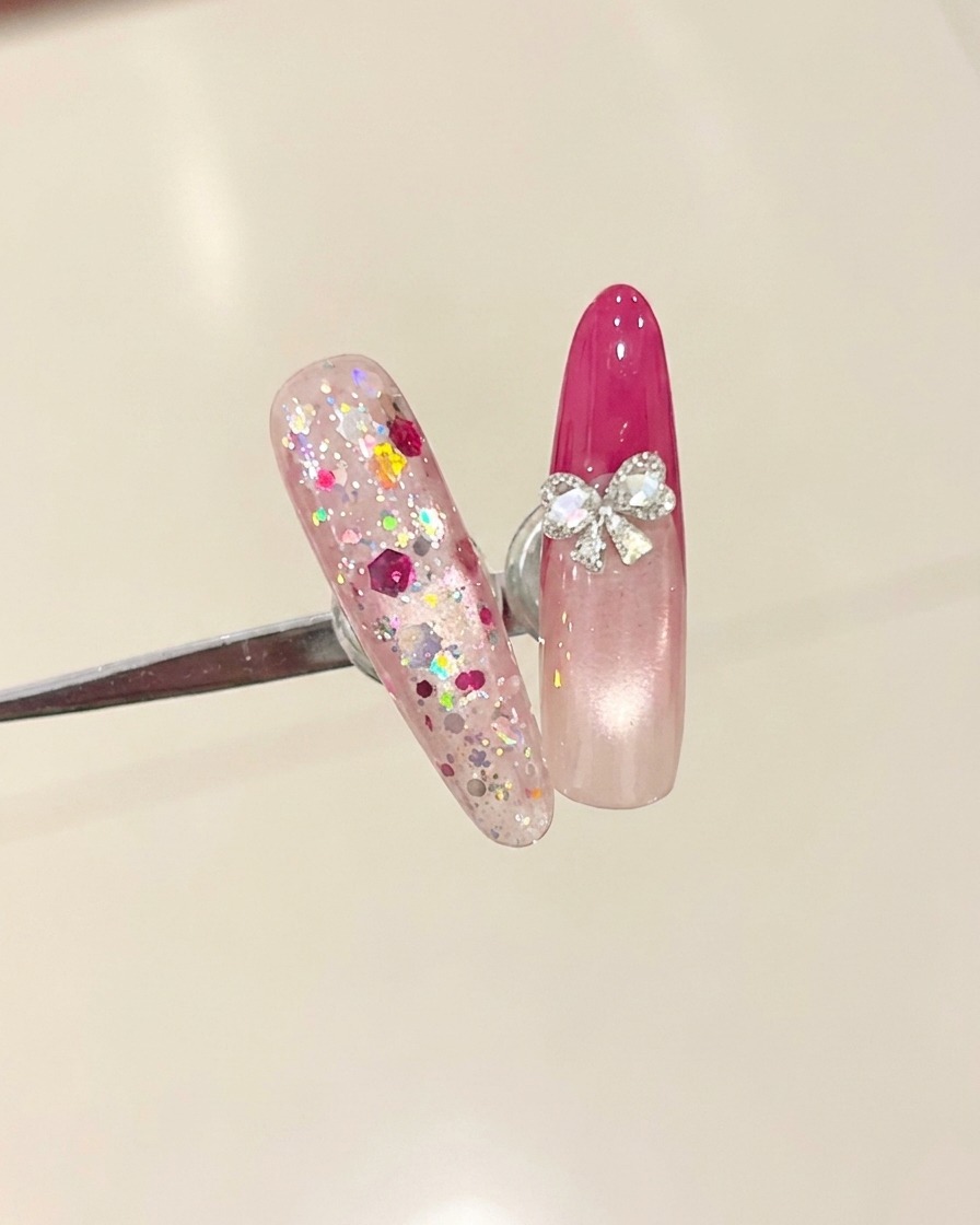 Un pinceau appliquant un top coat transparent sur un ongle avec une French rose rouge.