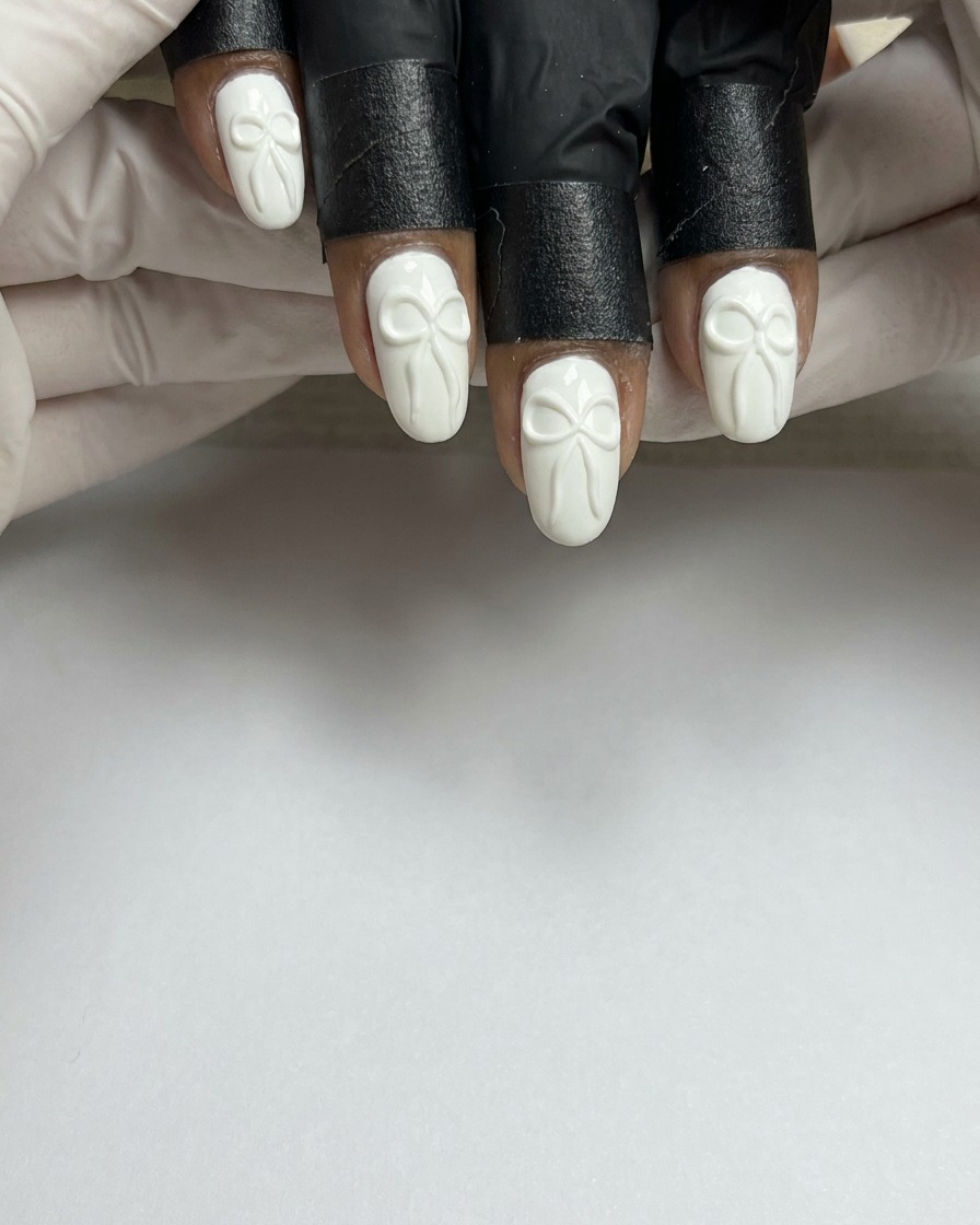 Un pinceau à ongles appliquant une couche lisse de vernis gel blanc sur un ongle naturel préparé.