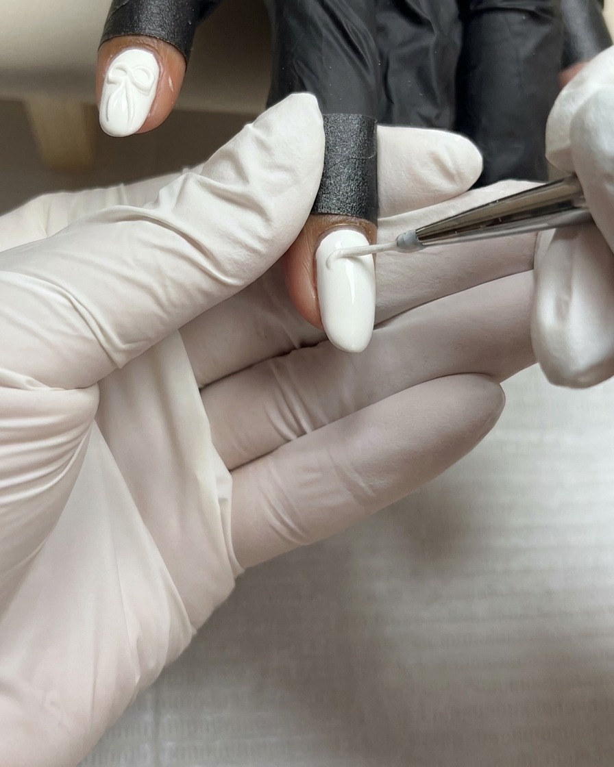 Une petite perle précise de gel de modelage blanc épais reposant au centre dun ongle peint en blanc.