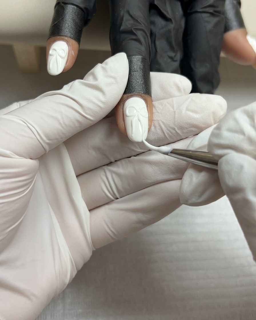 Gros plan dun pinceau liner fin ajoutant de fines lignes blanches à la surface dun nœud en gel 3D sur un ongle blanc.
