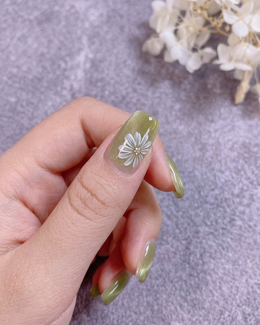 Un pinceau à ongles appliquant un top coat transparent rigide sur un design floral peint.