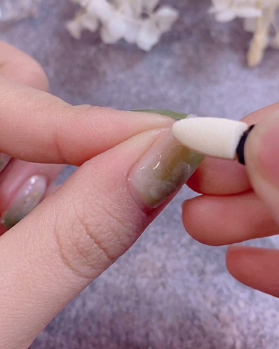 Un applicateur en silicone utilisé pour polir de la poudre chrome métallique sur un ongle peint au gel.