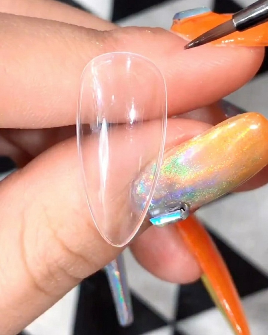Gros plan dun pinceau de détail appliquant du gel blanc pour former les pétales initiaux dune marguerite sur une capsule transparente.