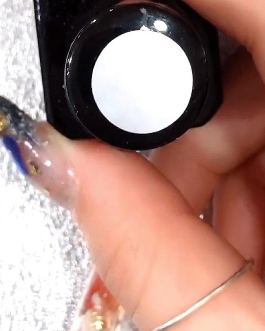 Gros plan dun pinceau appliquant une fine couche de gel transparent sur le design de pétales blancs existant.