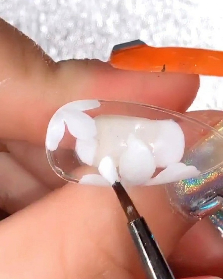 Pinceau de détail ajoutant plus de pétales en gel blanc sur le design initial pour augmenter le volume de la fleur.
