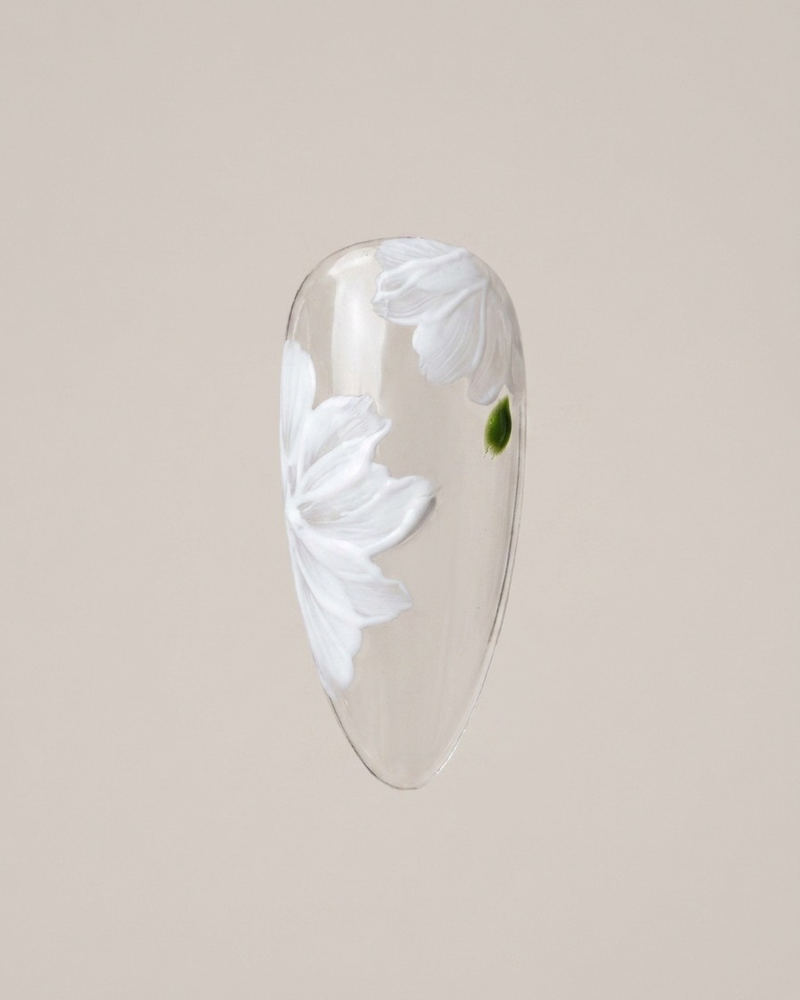 Un pinceau de détail peignant délicatement de petites feuilles vertes entre les pétales de la marguerite.