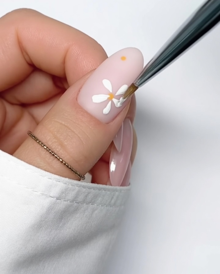 Gros plan dun ongle nude avec un point jaune parfaitement rond.