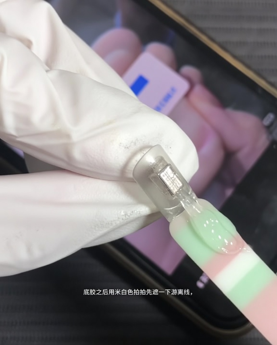 Un pinceau appliquant du gel blanc laiteux sur le bord libre dun ongle naturel.