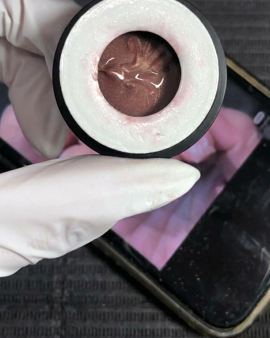 Gros plan sur un pot de vernis gel œil de chat couleur champagne.