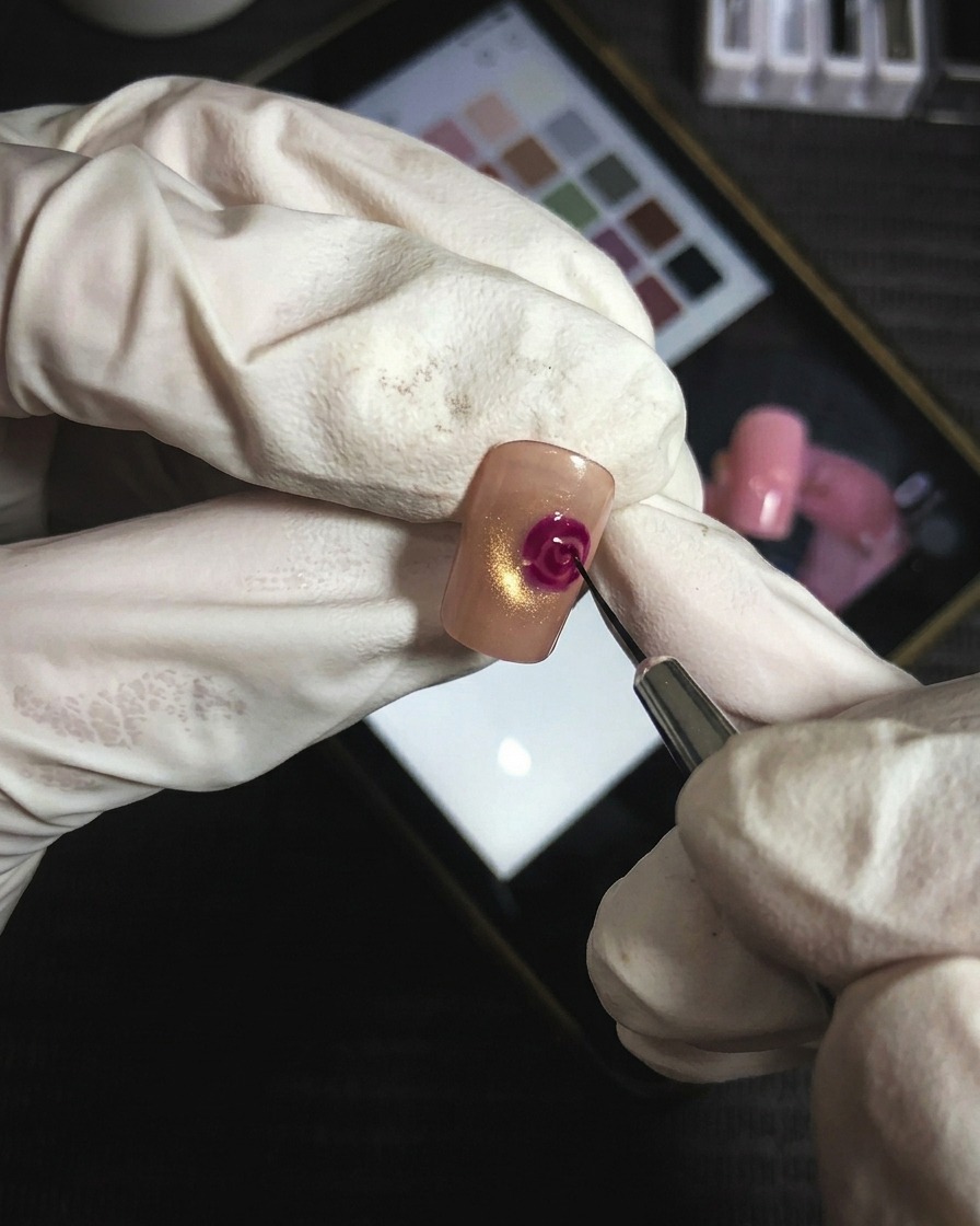 Un pinceau à pointe fine ajoutant des lignes précises de gel magenta pour accentuer les couches de pétales de la rose.