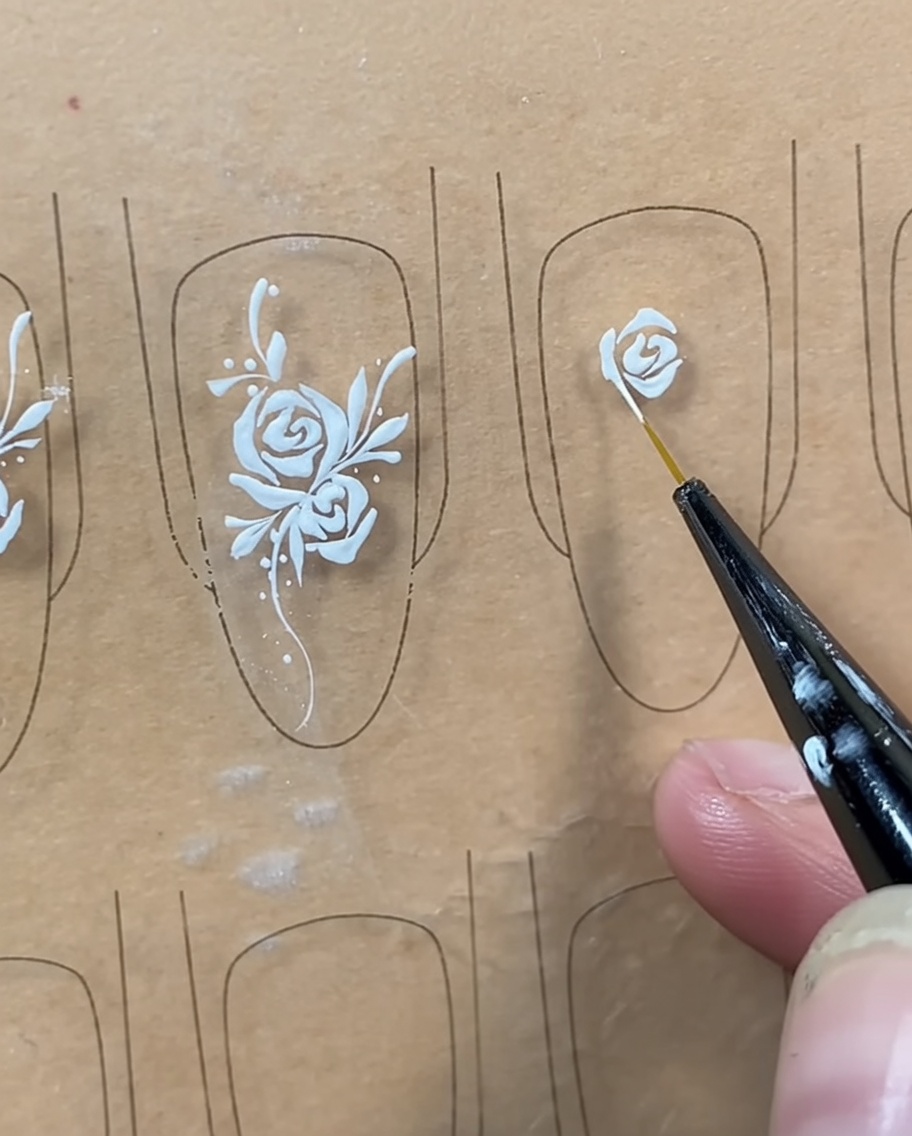 Un pinceau liner ajoutant une ligne courbe sous le bouton central pour fermer la forme de la rose.