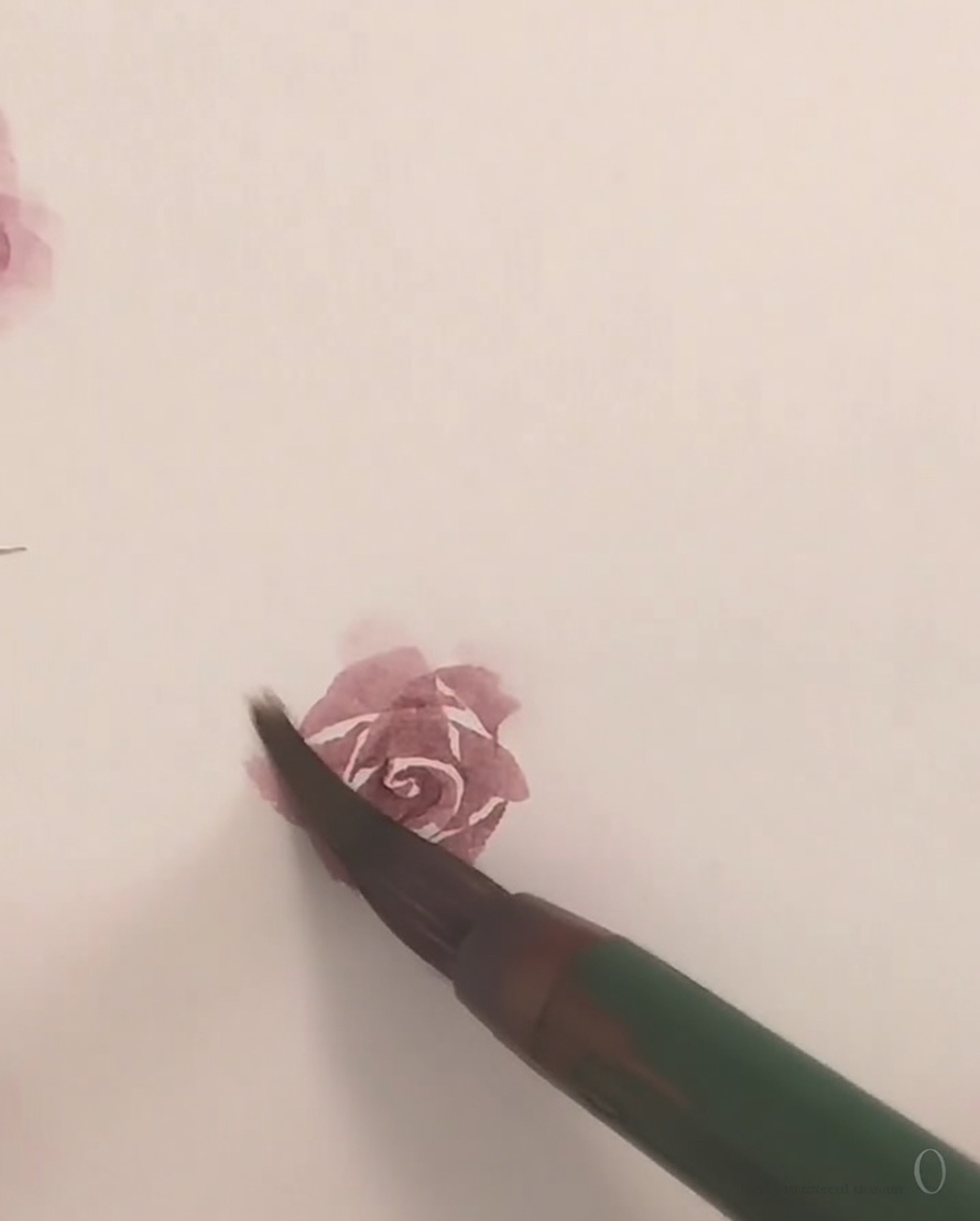 Un petit pinceau appliquant de la peinture aquarelle rose délicate pour former le pétale extérieur final dune rose.