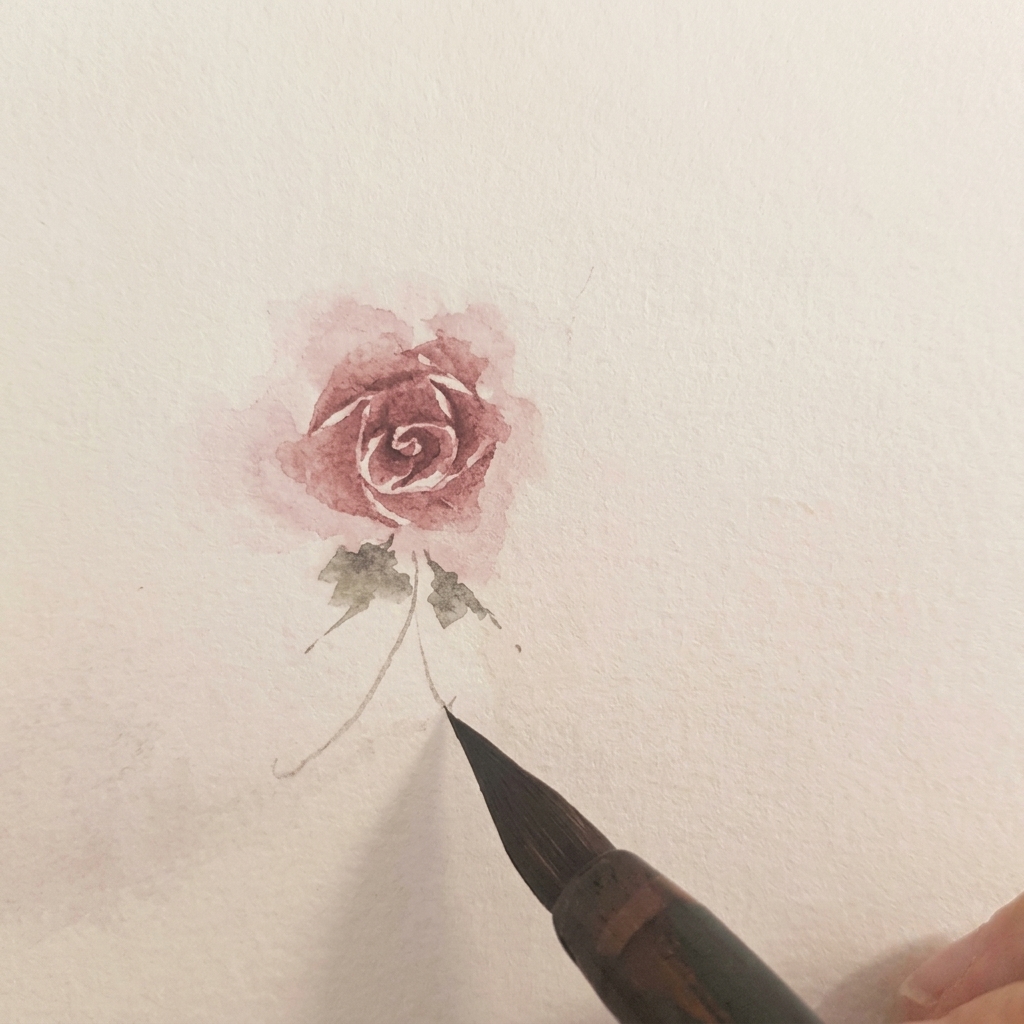 Deux petites feuilles aquarelle vertes peintes à la base dune rose terminée.