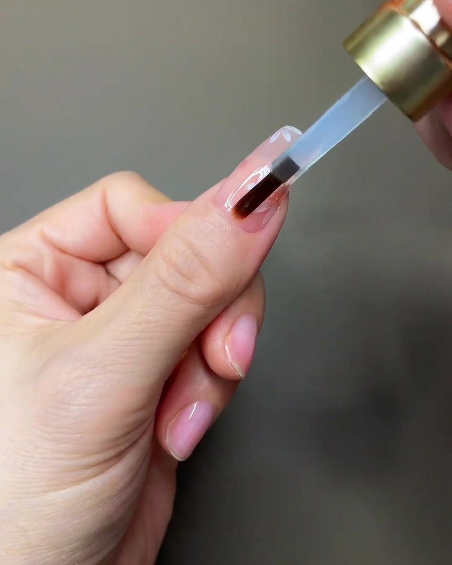 Une main plaçant un ongle sous une petite lampe UV/LED portable.