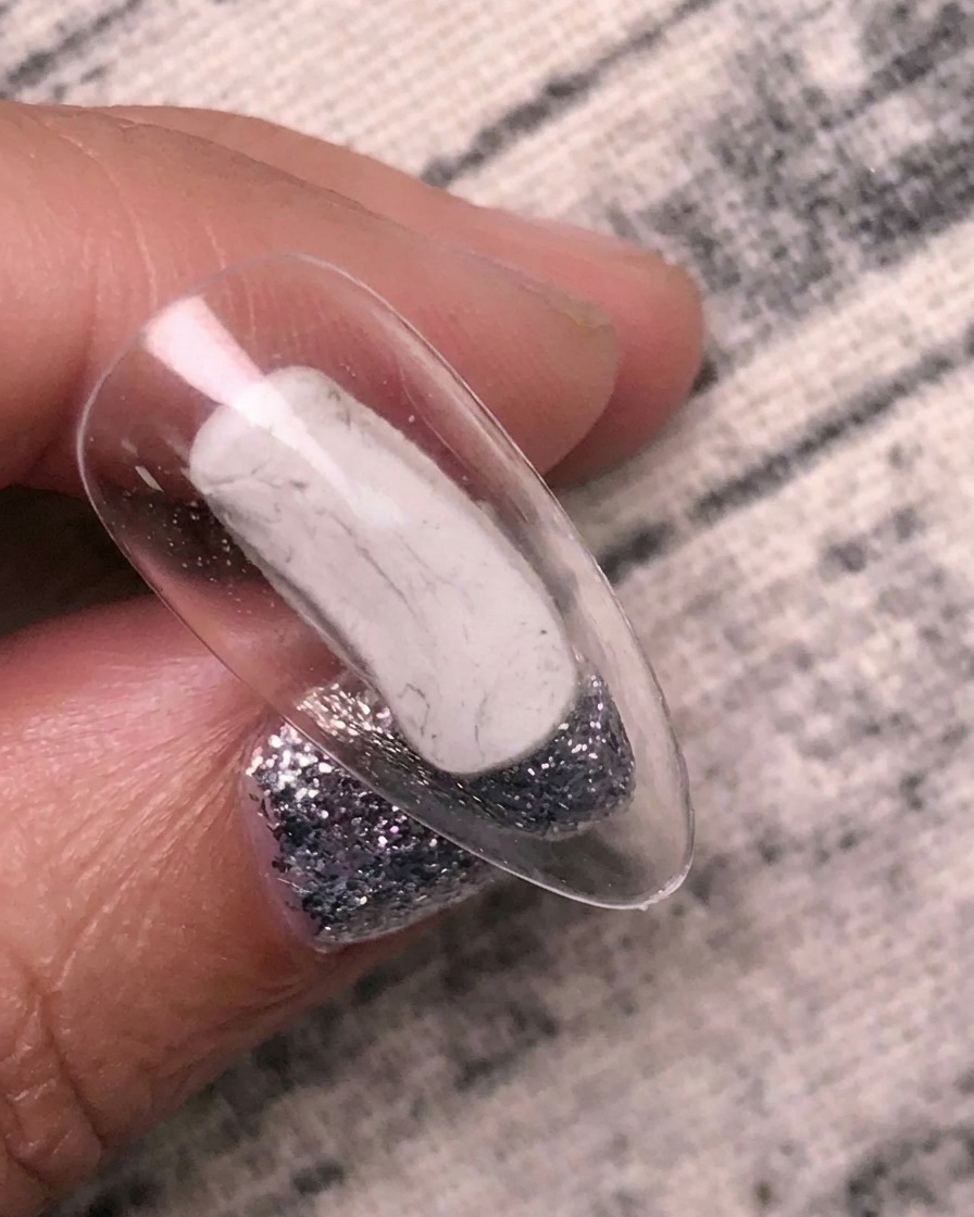 Un pinceau appliquant une colle de transfert transparente sur une capsule dongle.