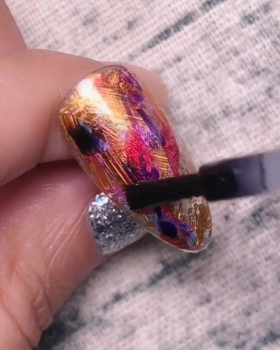 Gros plan dun ongle avec des points de gel bleu-violet, montrant les couleurs commençant à se mélanger et à sétendre dans la couche de base.
