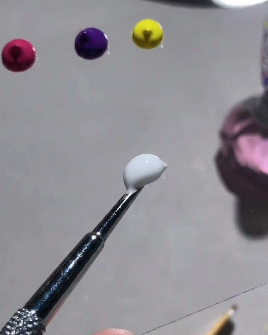 Une palette montrant diverses poudres colorées et un outil utilisé pour les mélanger avec du gel gypse blanc.