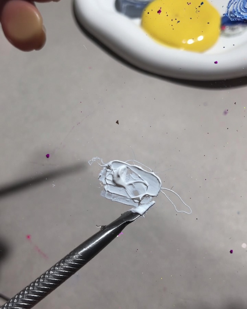Gros plan dun outil de mélange mélangeant du gel de peinture blanc et du gel fruit pour une texture crémeuse et lisse.