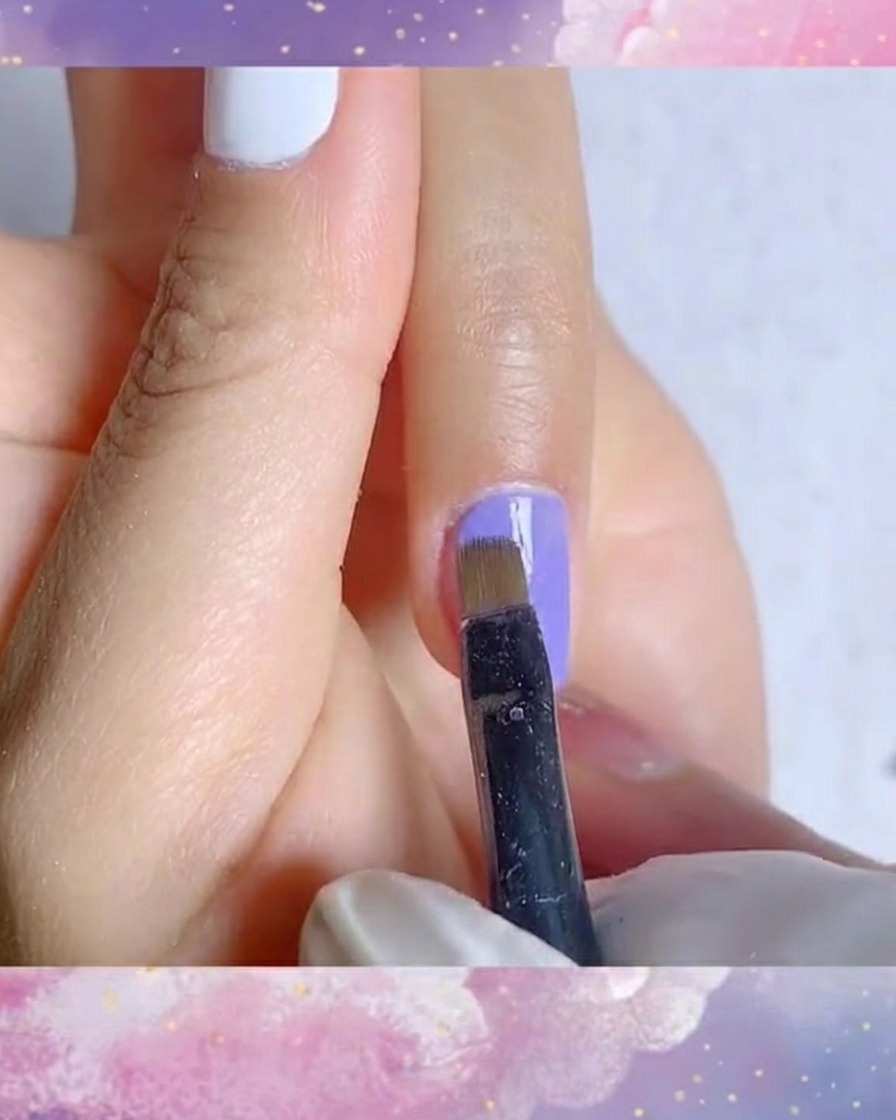 Un gros plan détaillé dun pinceau liner appliquant une seconde couche lisse de vernis gel bleu-violet vibrant.