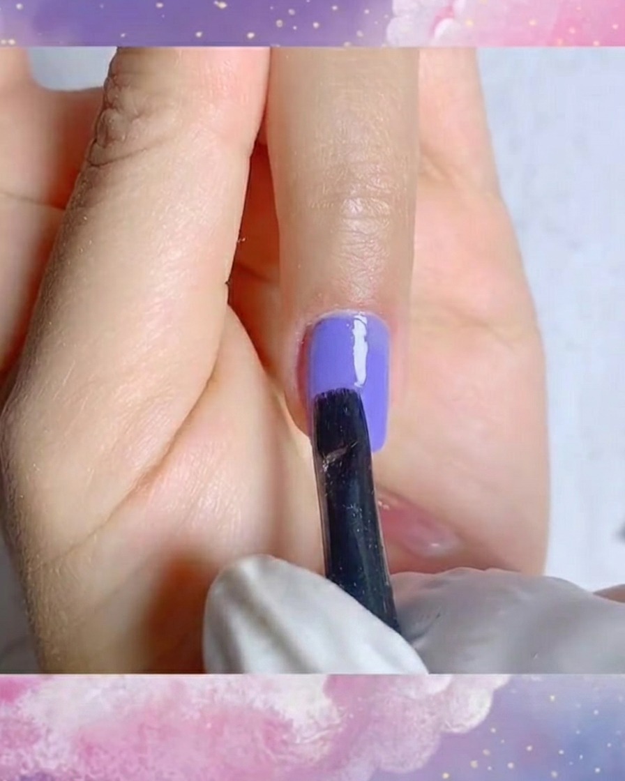 Un gros plan dun pinceau liner fin créant des traits précis de pétales blancs sur une base en gel violet.
