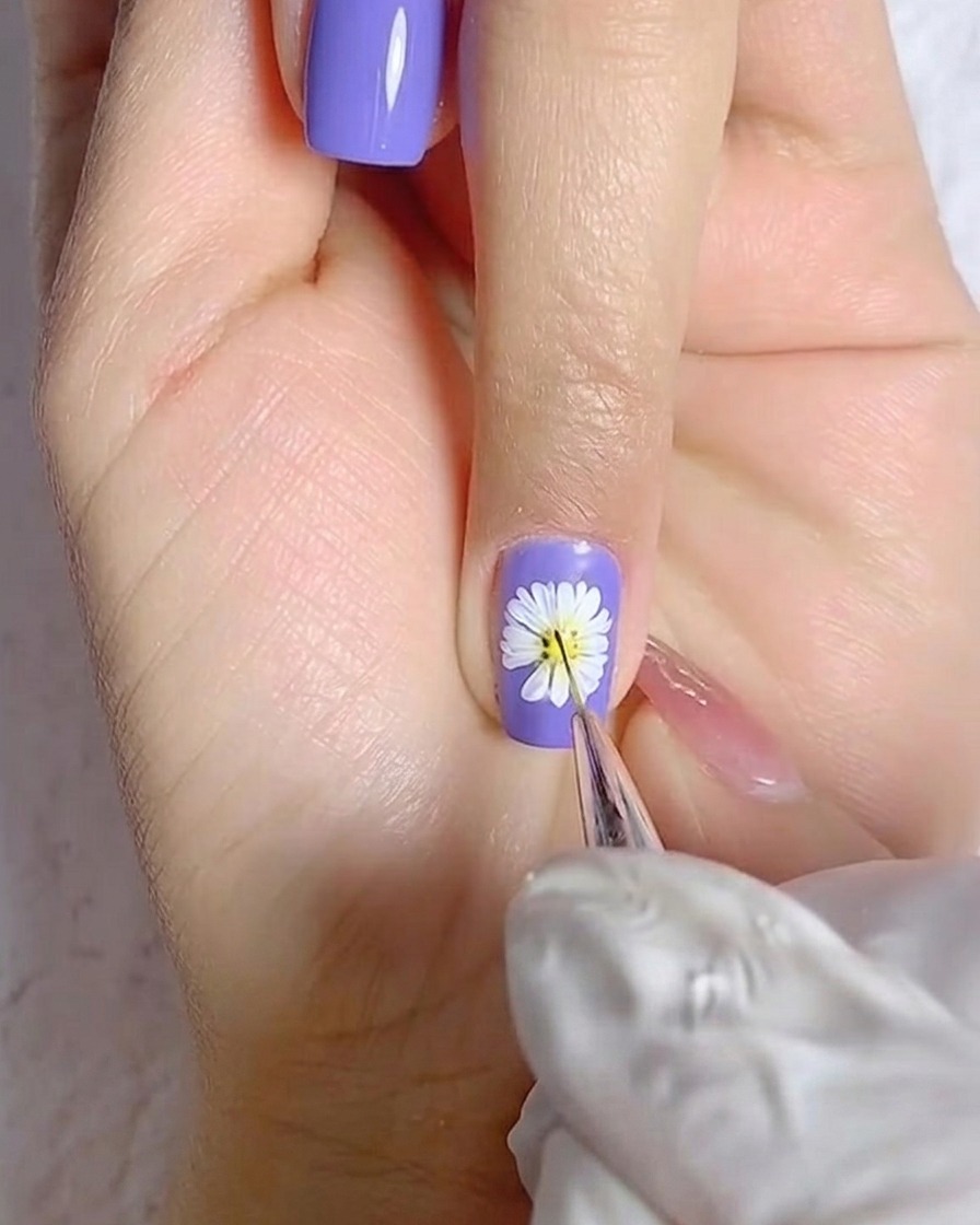 Un pinceau appliquant une couche lisse de vernis gel blanc sur un ongle de pouce.
