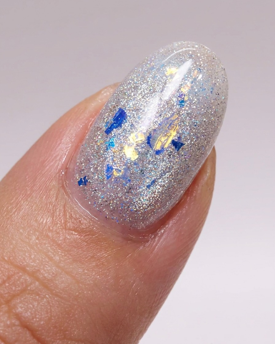 Un pinceau appliquant une couche lisse de top coat brillant sur un ongle décoré de flocons.