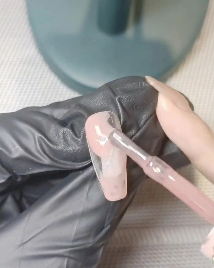 Un ongle sous une lampe UV pendant le processus de catalysation.