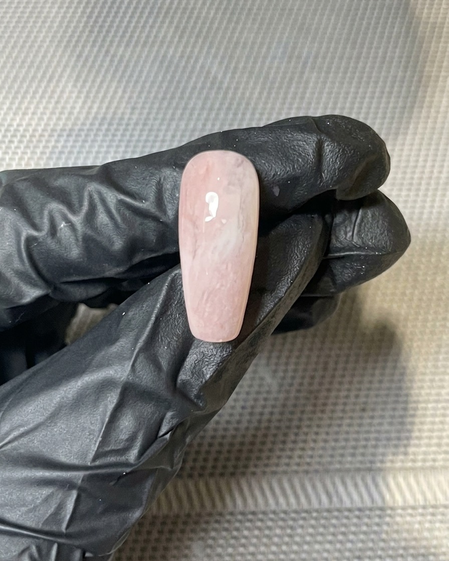 Gros plan de morceaux de feuilles dor pressés sur la surface collante dun ongle en gel.