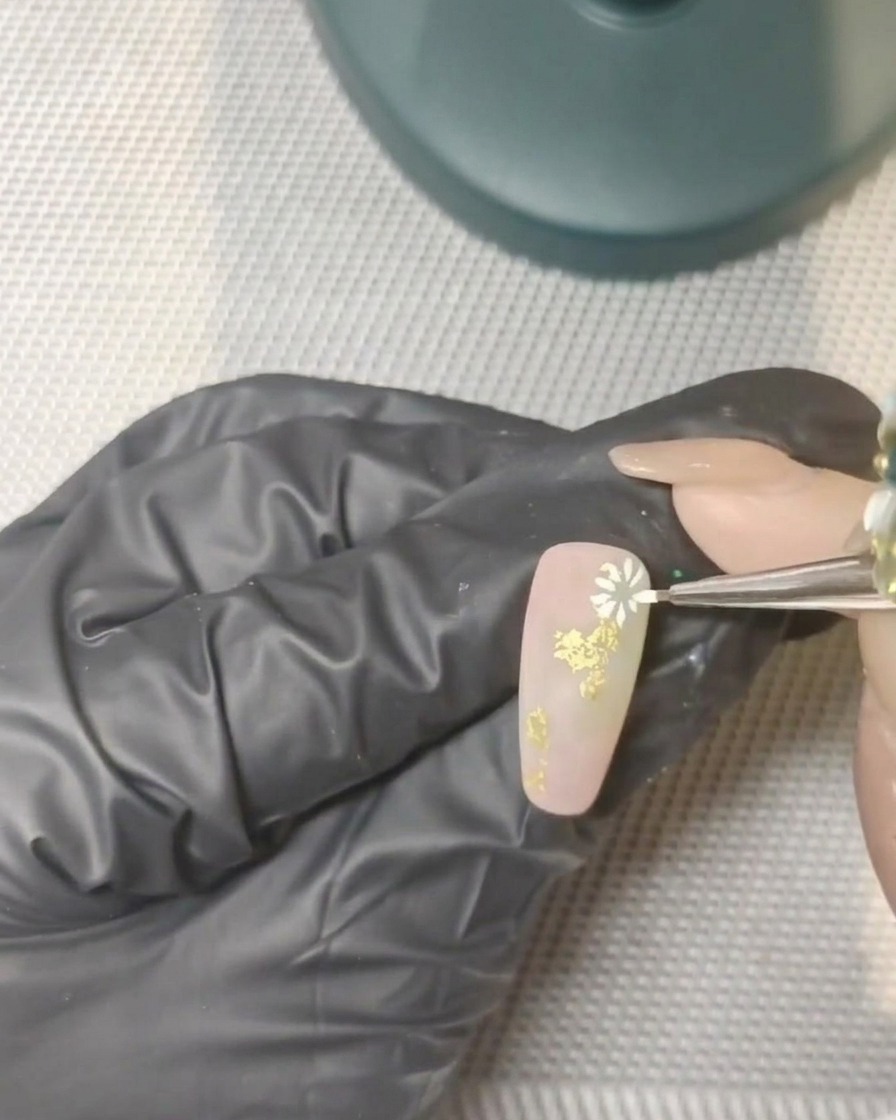 Une main avec des ongles décorés placée à lintérieur dune lampe UV professionnelle.