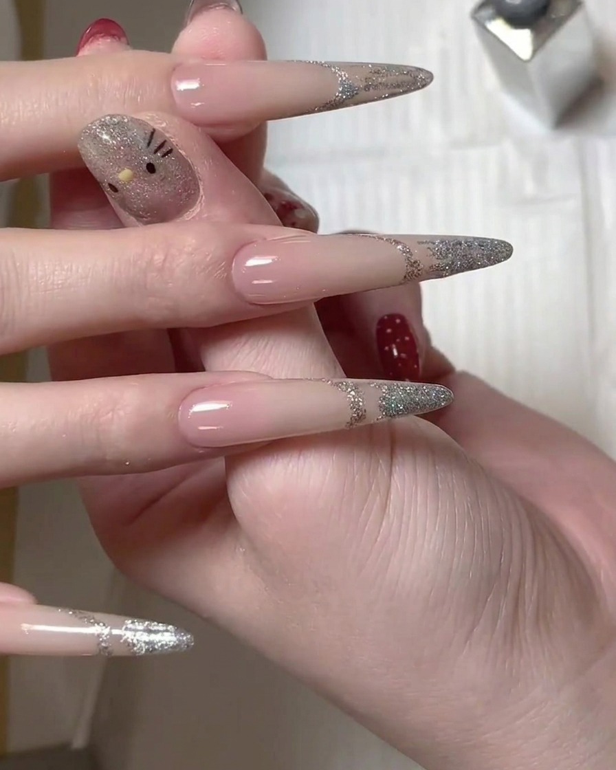 Un pinceau appliquant du vernis gel à paillettes argentées sur la pointe dun ongle long pour créer un design de French manucure.