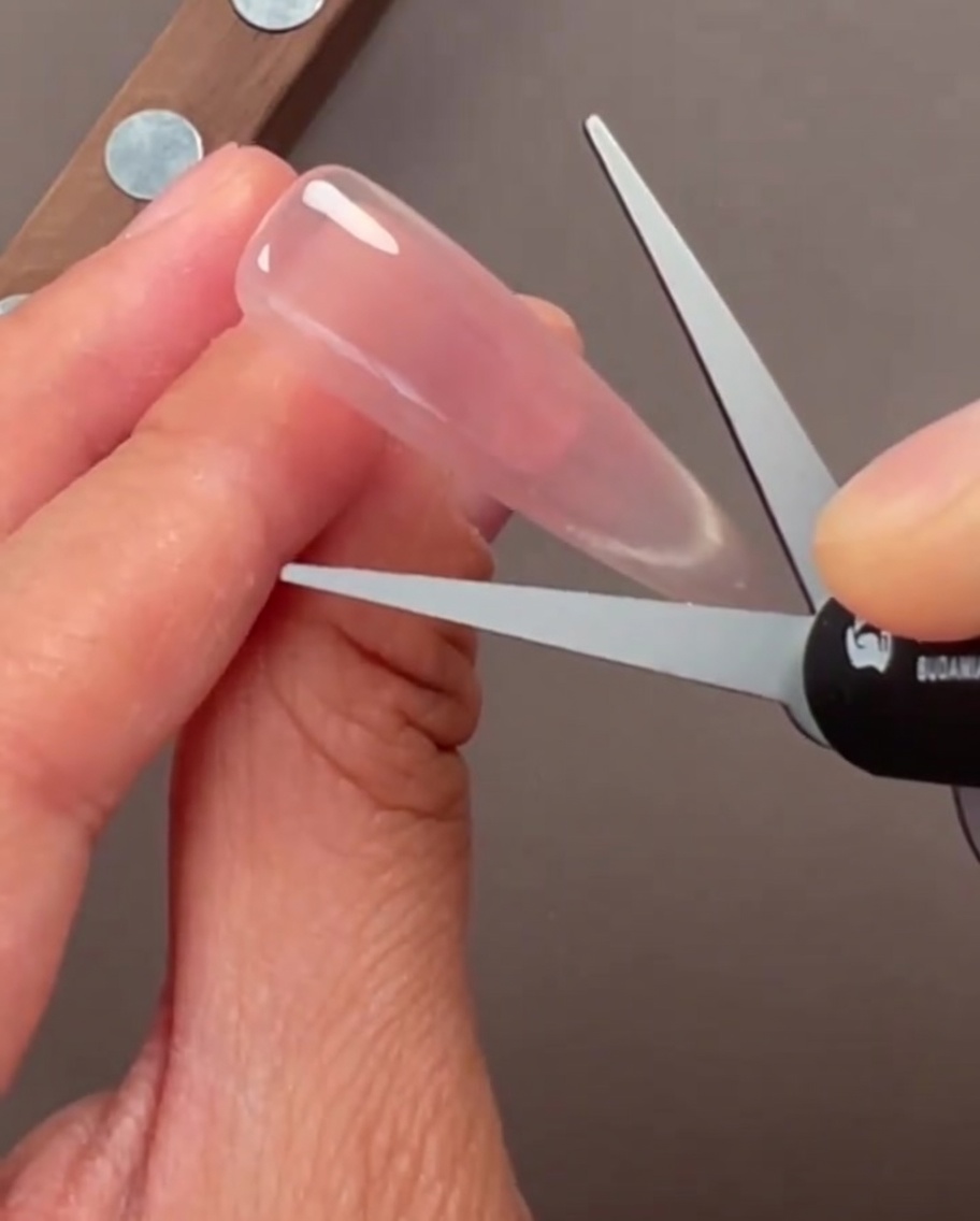 Gros plan sur des ongles avec une finition gel cat-eye type verre translucide.